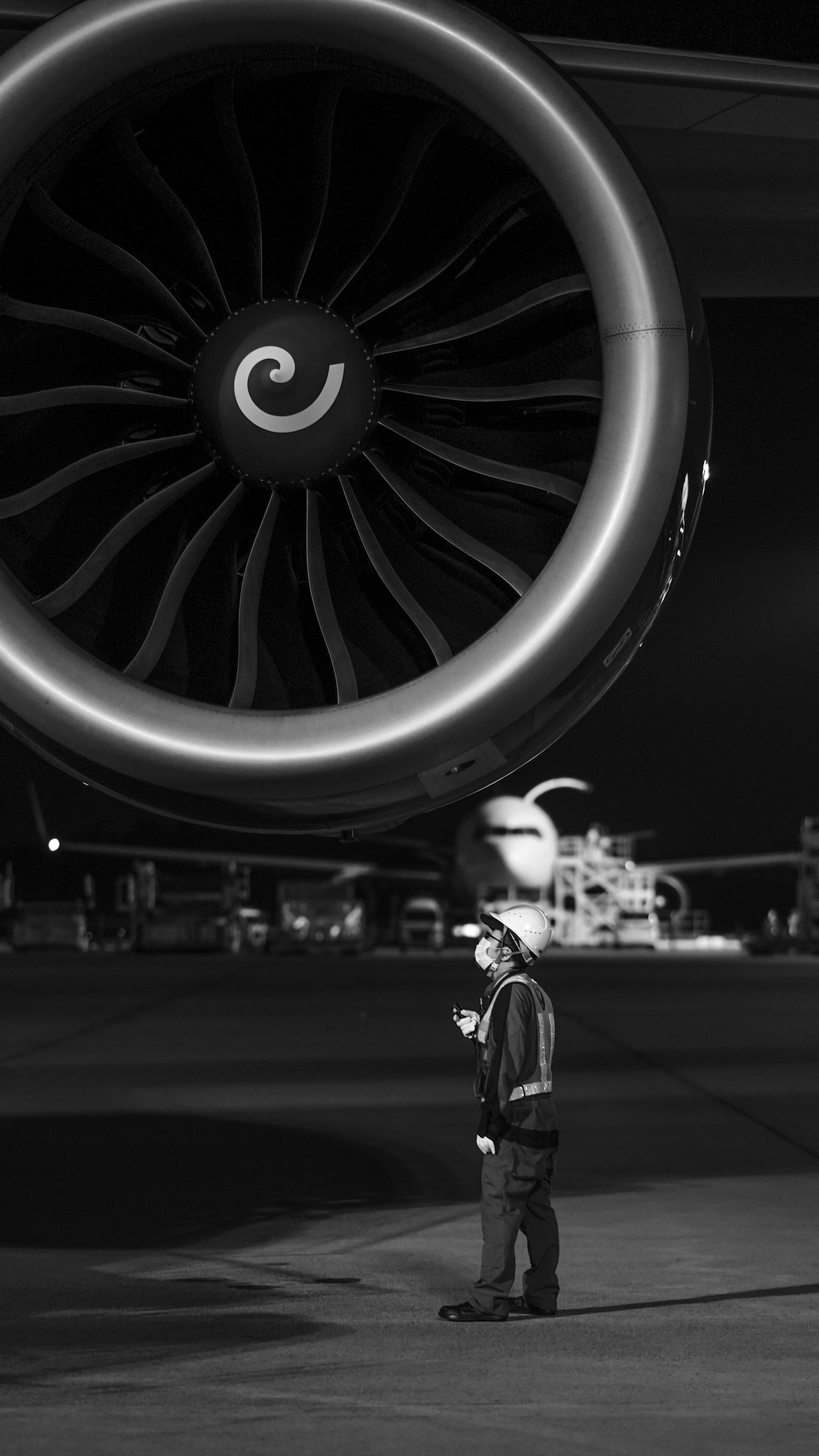 An engineer beside a jet engine turbine at night